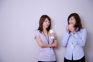 Two women drinking coffee at coffee break and smiling